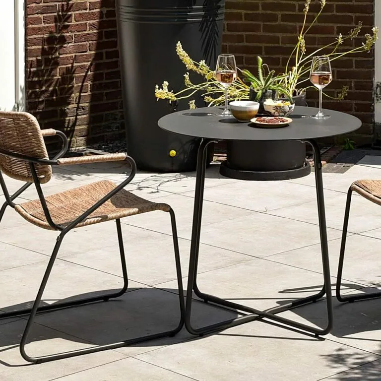 Dali Bistro Coffee Table placed outdoors with two dining chairs in a lifestyle setting