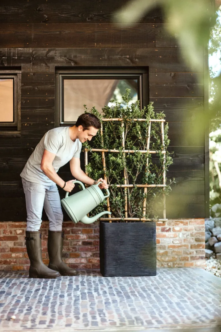 A man puts water into a garden pot placed in a lifestyle setting - Eco-Friendly Garden pots in Ireland