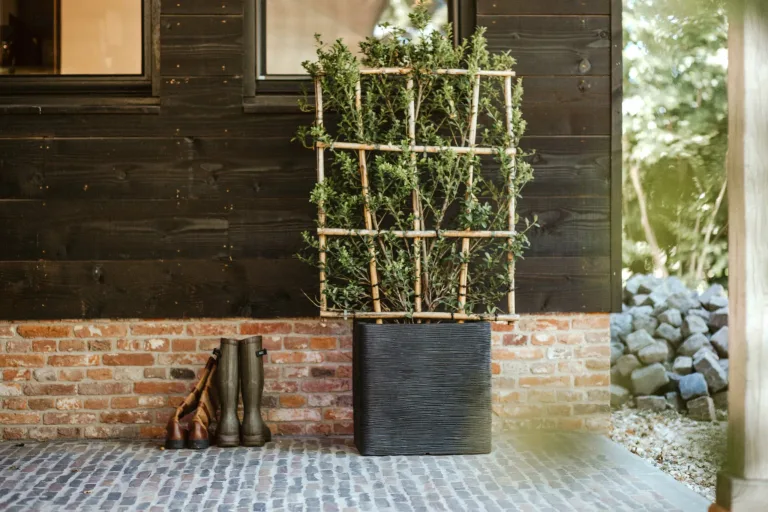 A recyclable, black outdoor garden square pot placed in a lifestyle setting