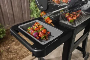 Weber Basin with cutting board for weber gas grills in lifestyle setting on a weber BBQ side shelf. real life cooking skewers.